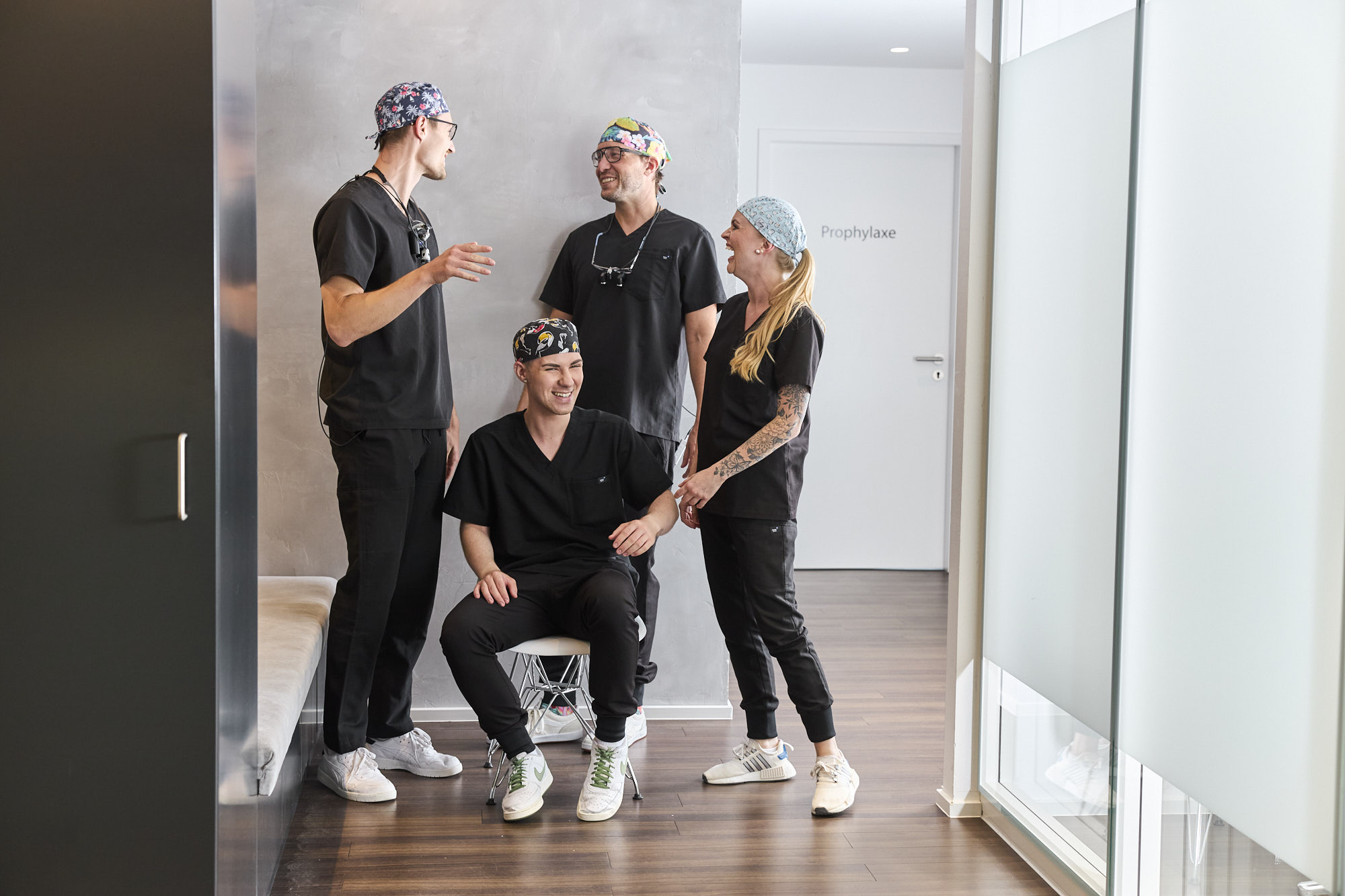 Oralchirurg und Behandlungsassistentin sitzen im Operationsraum. Der Chirurg greift nach einem Behandlungsinstrument.